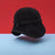 A black fleece bucket hat with a chin strap and toggle closure, floating against a split red and light blue background.
