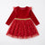 A red long-sleeve toddler dress with a velvet bodice, ruffled shoulder details, a gold glitter waistband, and a tulle skirt decorated with gold star patterns, shown on a plain white background.