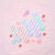 Four pastel striped socks arranged on a pink textured background with candy-themed props including peppermint candies and lollipops.