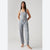 A woman modeling a sleeveless jumpsuit with a blue and beige floral print, standing against a light gray studio background.