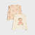 Two children's long-sleeve tops with ruffled shoulders, displayed on a light gray background. The top left is a light peach color with a repeating teddy bear print, and the top right is a cream color with a large central teddy bear graphic wearing a flower crown.