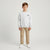 A young boy stands against a light gray studio background wearing a light gray crewneck sweatshirt with a black 'Chicago' logo on the chest, khaki pants, and white sneakers.