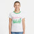 A young girl smiling and wearing a white ringer t-shirt with a green crew neck and a pink and green 'Hello from California' graphic on the front, paired with blue jeans, against a plain white background.