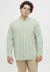 Man wearing a light green button-up shirt and beige pants on a white background