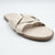 A single beige slide sandal with wide crisscrossing straps and a low flat heel, photographed on a light gray studio background.