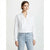 A woman modeling a white long-sleeve wrap-style blouse with a high collar and light-wash blue jeans against a plain light gray studio background.