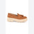 A single tan suede loafer with a matching fabric tassel on the vamp and a chunky off-white lug sole, shown in profile against a plain white background.