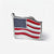 A small enamel lapel pin shaped like a waving American flag, with a silver-tone metal outline and red, white, and blue enamel details, photographed on a clean white background.