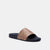 A single slide sandal with a tan and brown monogram patterned strap and a black sole, shown against a plain light gray background.
