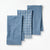 Three folded blue kitchen towels with different textured and patterned designs, arranged overlapping on a clean white background.