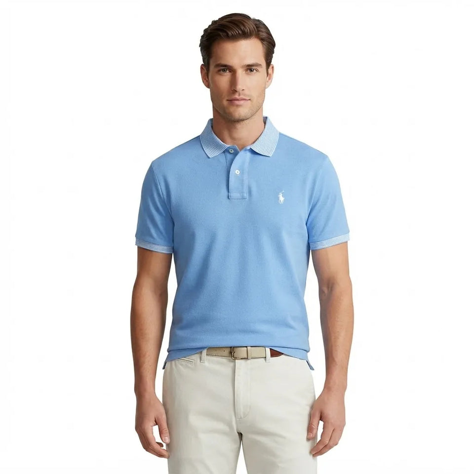 A man wearing a light blue short-sleeve polo shirt with a white embroidered polo player logo on the chest, paired with beige pants, against a plain white background.