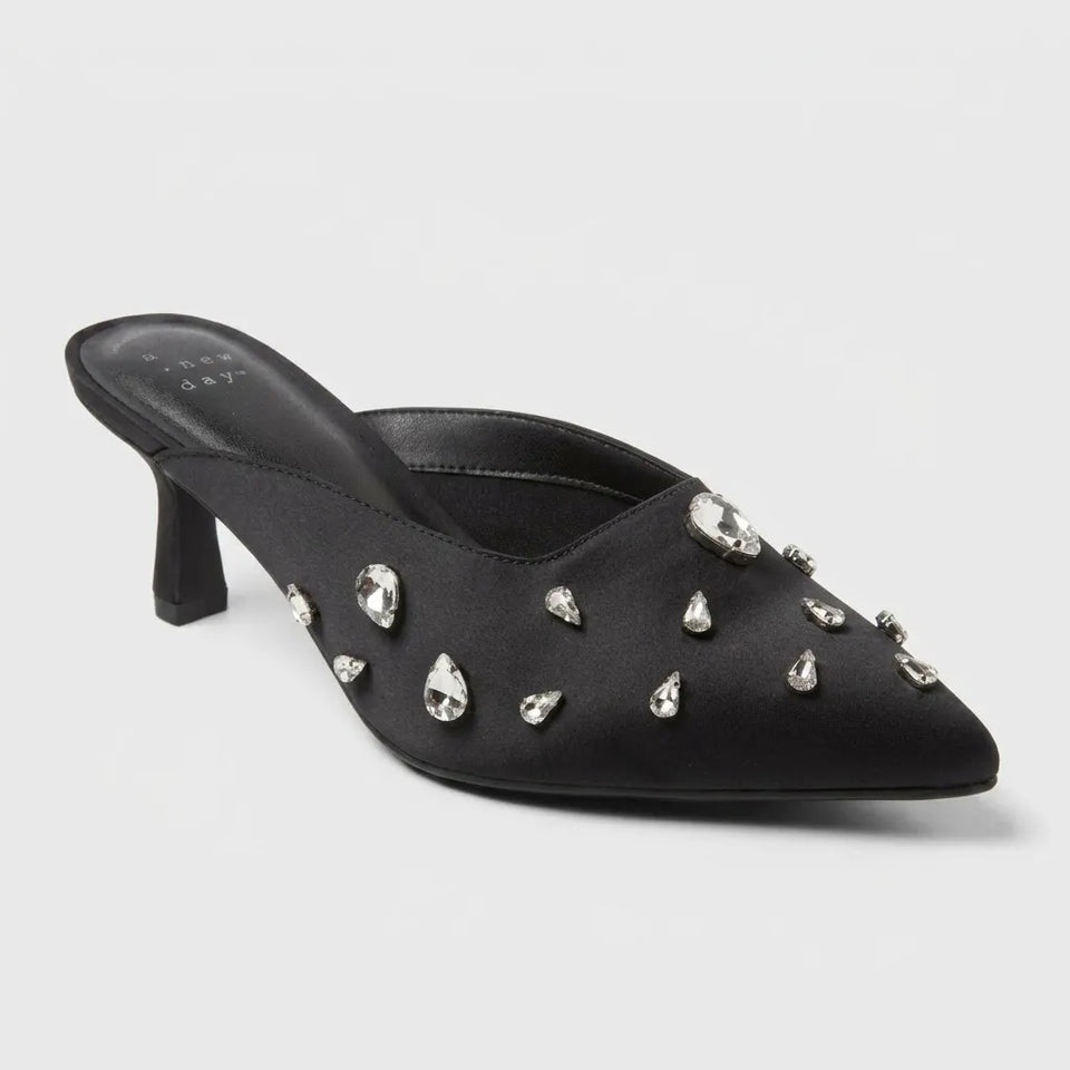 A single black satin pointed-toe mule high heel decorated with silver rhinestone studs, shown on a light gray background.