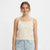 A woman wearing a cream-colored knit camisole top with small embroidered stars in multiple colors, paired with light-wash blue jeans, against a plain white studio background.