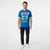 A man modeling a bright blue graphic t-shirt featuring Stitch from Disney's 'Lilo & Stitch' with 'STITCH' printed in large white letters and a colorful cartoon graphic. He is wearing dark wash jeans and white sneakers against a plain white studio background.