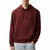 A man wearing a dark red/burgundy Calvin Klein hoodie with a tonal embroidered logo on the chest, paired with light blue jeans, against a plain white background.