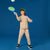 A child wearing a beige sweatshirt and matching sweatpants with a green cap is playing with a blue paddle against a solid blue studio background.