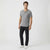 A man modeling a short-sleeve gray henley t-shirt, black pants, and white sneakers against a plain white studio background.