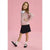 A young girl modeling a pink knit cardigan with white floral embroidery and a white lace collar, paired with a black skirt, white socks, and black Mary Jane shoes, set against a solid pink studio background.