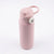 A matte light pink insulated water bottle with a matching pink flip-top lid and carrying loop, featuring a small white circular logo button on the side, set against a plain white background.