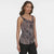 A woman modeling a sleeveless scoop-neck top with a black, beige, and white wavy geometric pattern, paired with black pants, against a light gray studio background.
