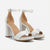 A pair of white leather block-heel sandals with ankle straps and open toes, displayed on a clean white background.