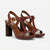 A pair of women's block-heel sandals in dark brown leather with gold-tone buckle details, displayed on a clean light gray background.