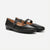 A pair of black leather Mary Jane flats with a pointed toe and a silver-tone buckle strap, shown on a light gray background.