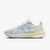 A Nike running shoe in light gray and white mesh with a beige heel counter and a blue 'AIR ZOOM' text detail on the midsole, shown against a light gray background.