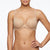 A woman wearing a seamless, underwire bra in a light beige/nude color, shown from the nose down against a plain white background.