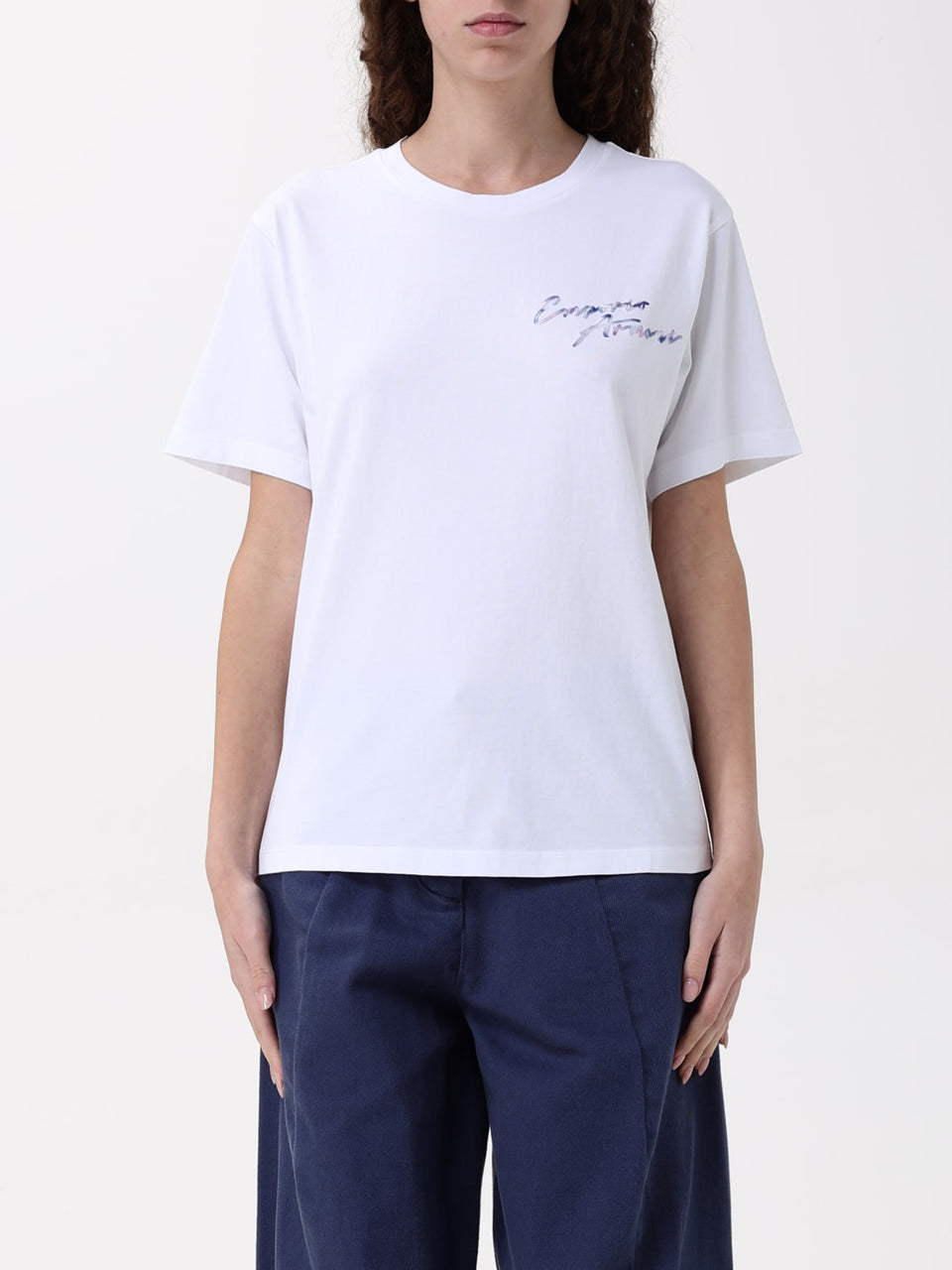 Person wearing a white t-shirt with text and navy pants on a white background