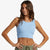 A woman modeling a light blue ribbed knit crop top against a clean white background.