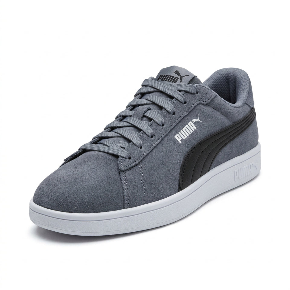 A Puma Suede Classic sneaker in dark gray suede with a black synthetic side stripe and a light gray sole, shown from the side on a light gray background.