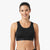 A woman wearing a black sports bra against a plain white background.