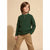 A young boy wearing a dark green ribbed knit long-sleeve henley sweater and tan pants, standing against a solid beige background.