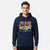 A man wearing a navy blue pullover hoodie with a colorful 'Pokémon' graphic on the chest, featuring the red-orange logo and several classic Pokémon characters, set against a plain light gray background.