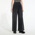 A model wearing high-waisted, wide-leg charcoal gray denim pants with a striped top and black platform shoes, photographed against a clean white studio background.