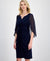 Woman wearing a navy blue dress with sheer sleeves on a white background