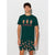 A man modeling a dark green short-sleeve t-shirt and matching shorts set. The t-shirt features three gingerbread men illustrations with the text 'So baked for that!' in red.