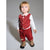 A toddler standing against a plain gray studio background, wearing a red corduroy vest and matching corduroy pants over a white long-sleeve shirt, with a small red bow tie and tan boots.