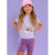 A young girl modeling a light purple t-shirt with a rainbow sequin graphic, matching purple biker shorts, and a pink baseball cap, set against a solid lavender background.