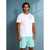 A man modeling a white short-sleeve t-shirt with a small yellow and blue logo on the left chest, paired with light blue shorts featuring a yellow banana print, set against a blue-gray wall.