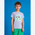 A young boy wearing a heather gray t-shirt with a green and black soccer graphic that reads 'Soccer Academy Football', paired with green shorts, standing against a solid blue background.