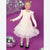 A young girl with blonde hair in a ponytail stands on a purple studio background wearing a long-sleeve cream dress with a sparkly tulle skirt. She is surrounded by silver disco balls and hanging tinsel.