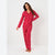 A woman modeling a red long-sleeve pajama set with a white dalmatian spot pattern, standing against a plain white studio background.