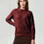 A woman wearing a textured, cable-knit crewneck sweater in a deep burgundy red, paired with a brown skirt, against a light gray studio background.