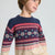 A child wearing a navy blue knit sweater with a red and cream Nordic/Fair Isle pattern across the chest and sleeves, photographed against a light gray studio background.