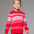 A young boy wearing a red and white patterned knit sweater, standing against a solid gray studio background.