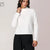 A woman wearing a white ribbed mock neck sweater and black pants, standing against a light beige studio background. A small 'AI' watermark is visible in the top-left corner.