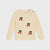 A cream-colored knit sweater for toddlers, featuring embroidered cherry motifs with red berries and dark green leaves, displayed on a light gray background.