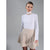 A model wearing a white long-sleeve mock neck top and a beige textured flared mini skirt with sequins, set against a solid gray studio background.